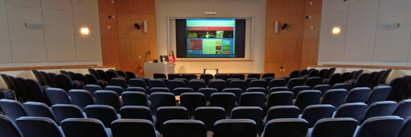 auditorium with speaker at the front and powerpoint slides